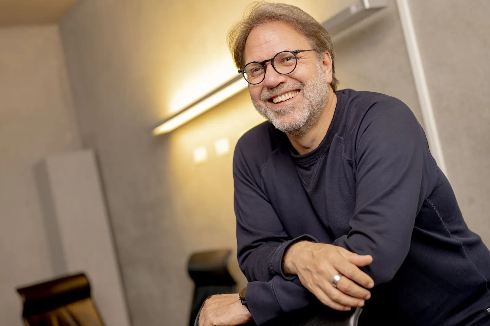 Ralf Lanwehr lehnt lächelnd an einem Stuhl